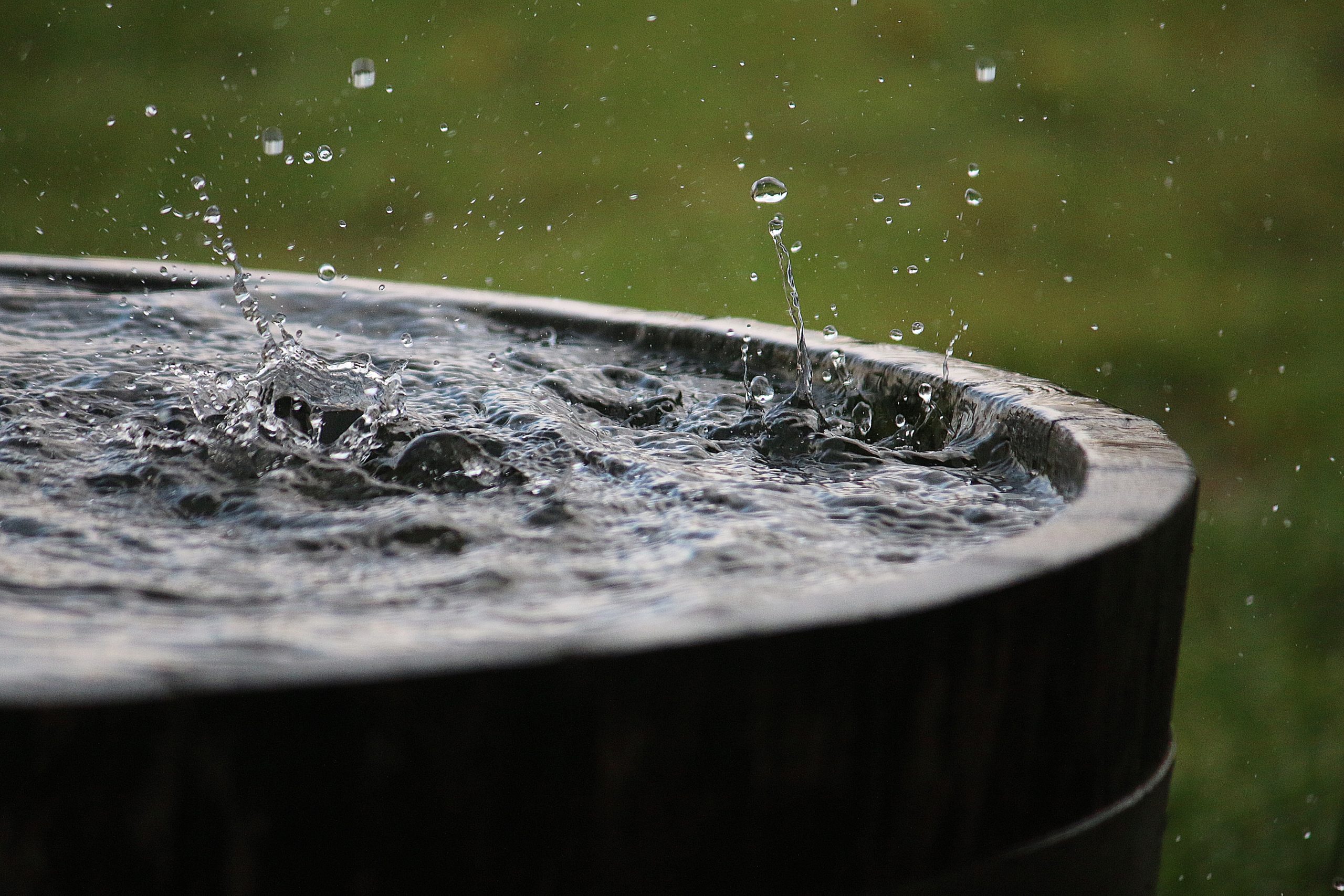 rain is falling in a wooden barrel full of water in the garden