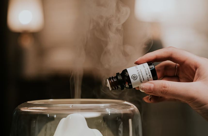 person adding some essential oil to the diffuser