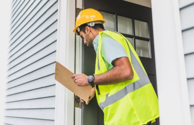 man inspecting the door of a house