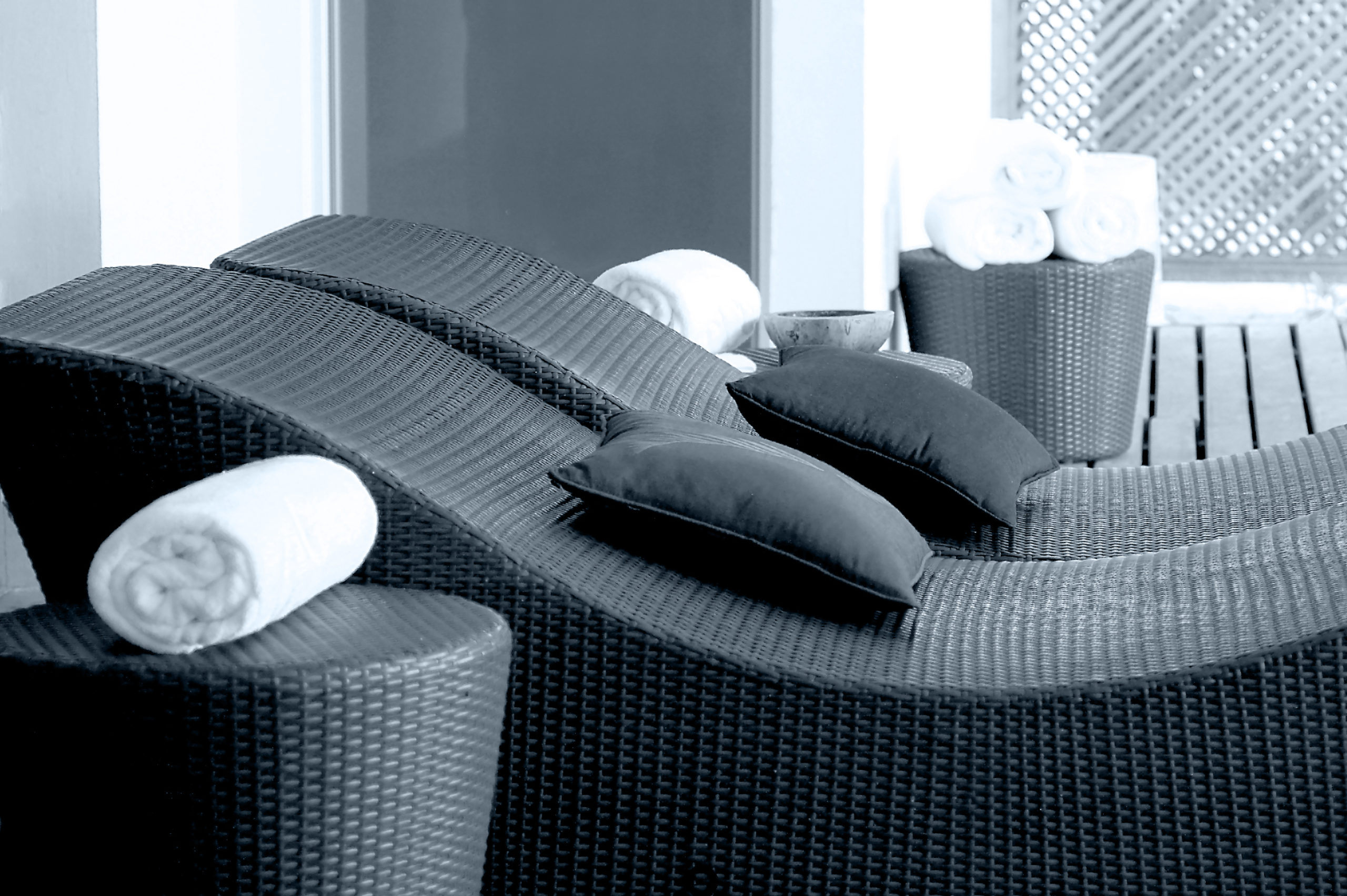 black relaxation rattan bed with black pillows, white towel