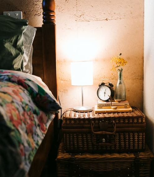 rustic rattan storage, lampshade, books, vase, and a bed