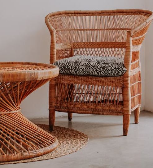 a wicker chair with a gray cushion and a wicker table