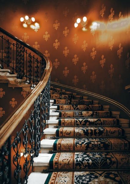 A Victorian carpeted staircase with stair rods in place.