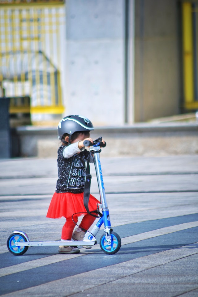 toddler on a scooter wearing helmet