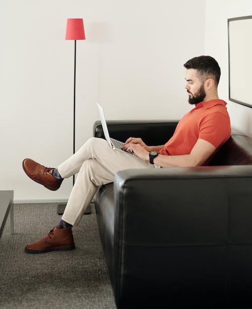 man sitting on black leather couch