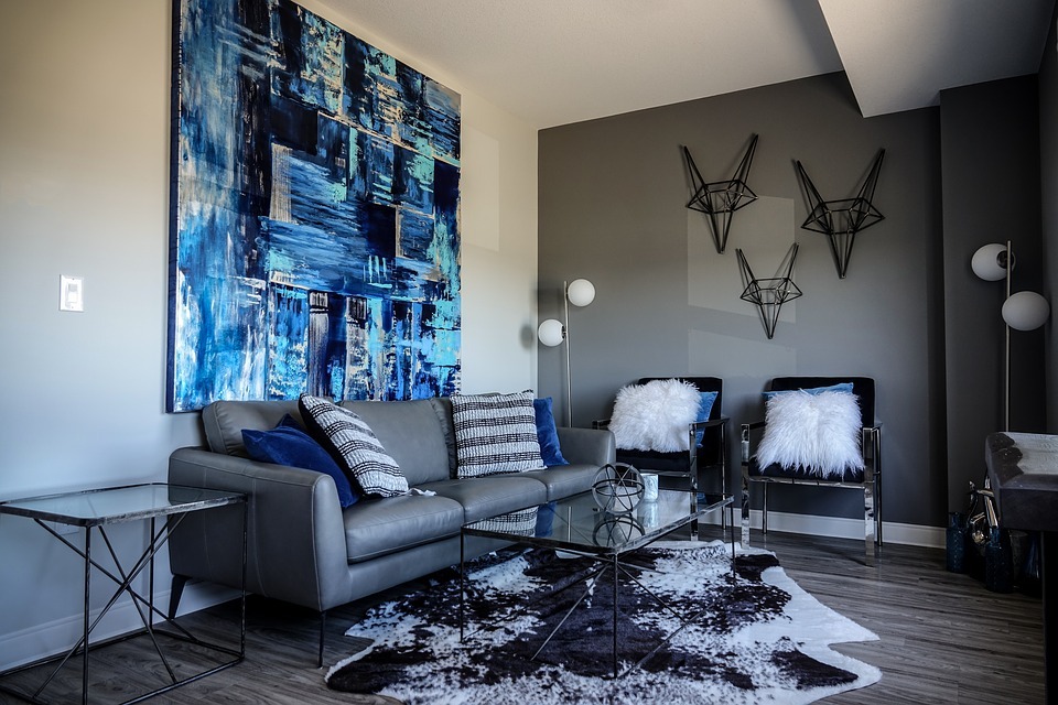 A small living room with a large abstract artwork on one wall and some geometric wall décor at another wall