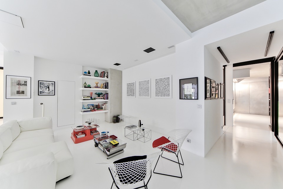 A Scandinavian-style living room with white walls, white furniture and some black and red accents