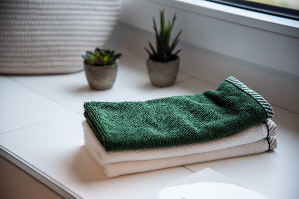 a pair of two white towels and a green towel on the top