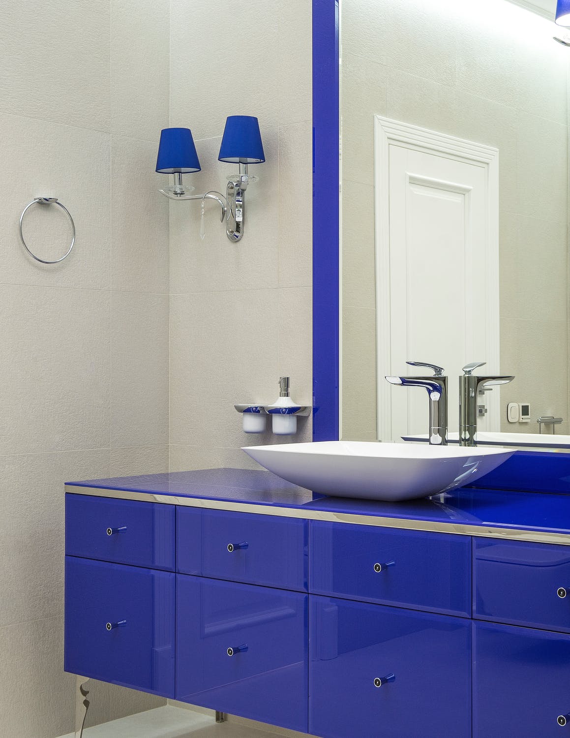 Blue themed bathroom with sink, lamps and towel hook 