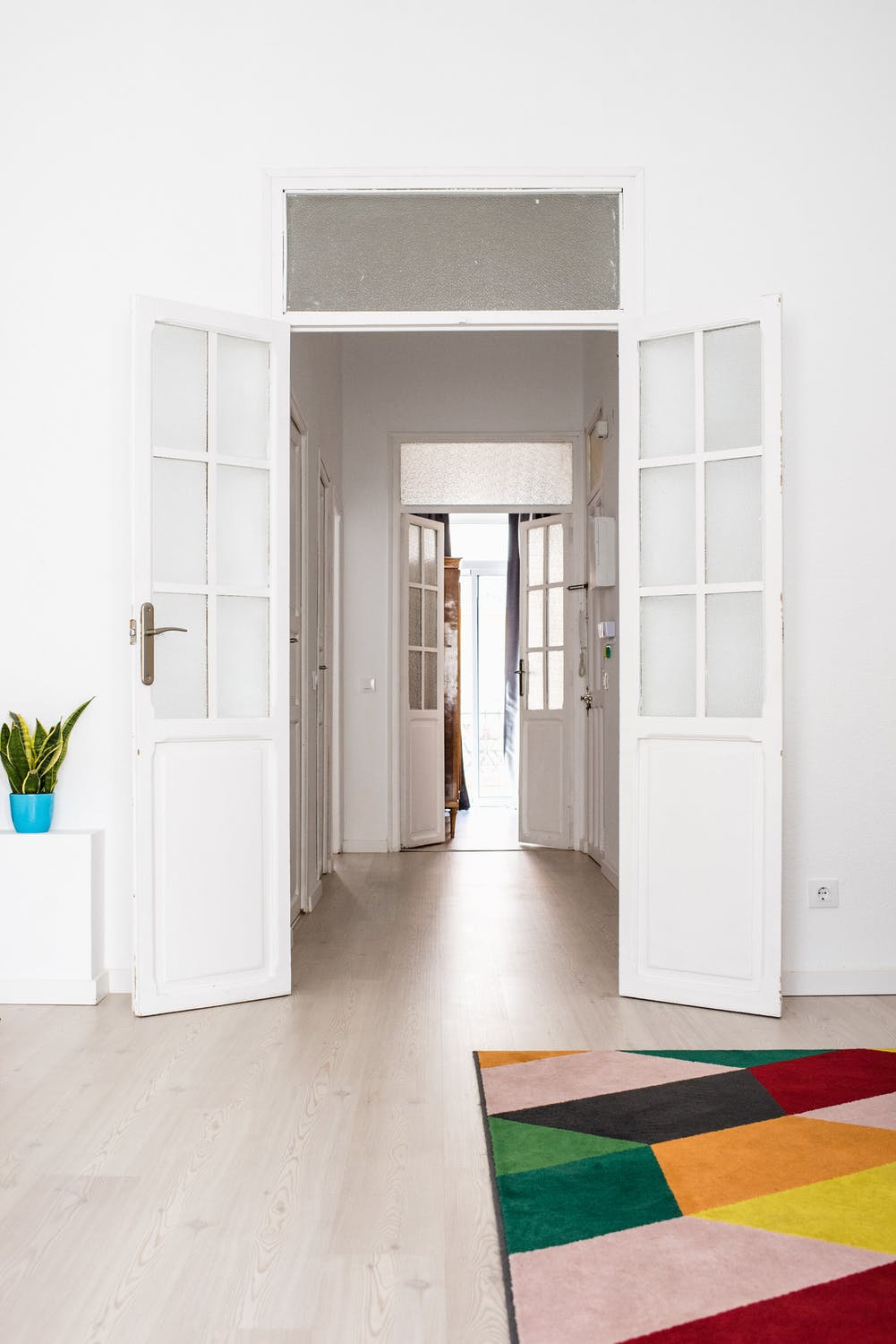 Colorful rug placed in a white room with wide-open doors. 