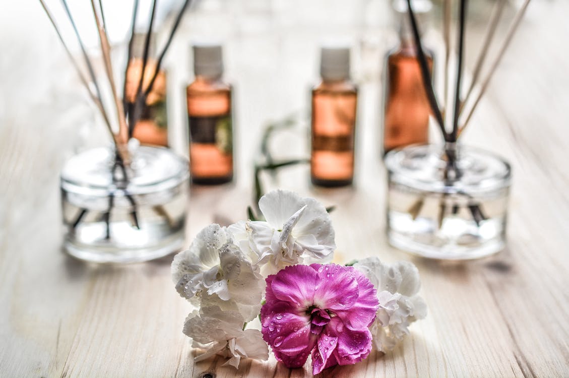 Scented candles, a flower, and perfumes on a table