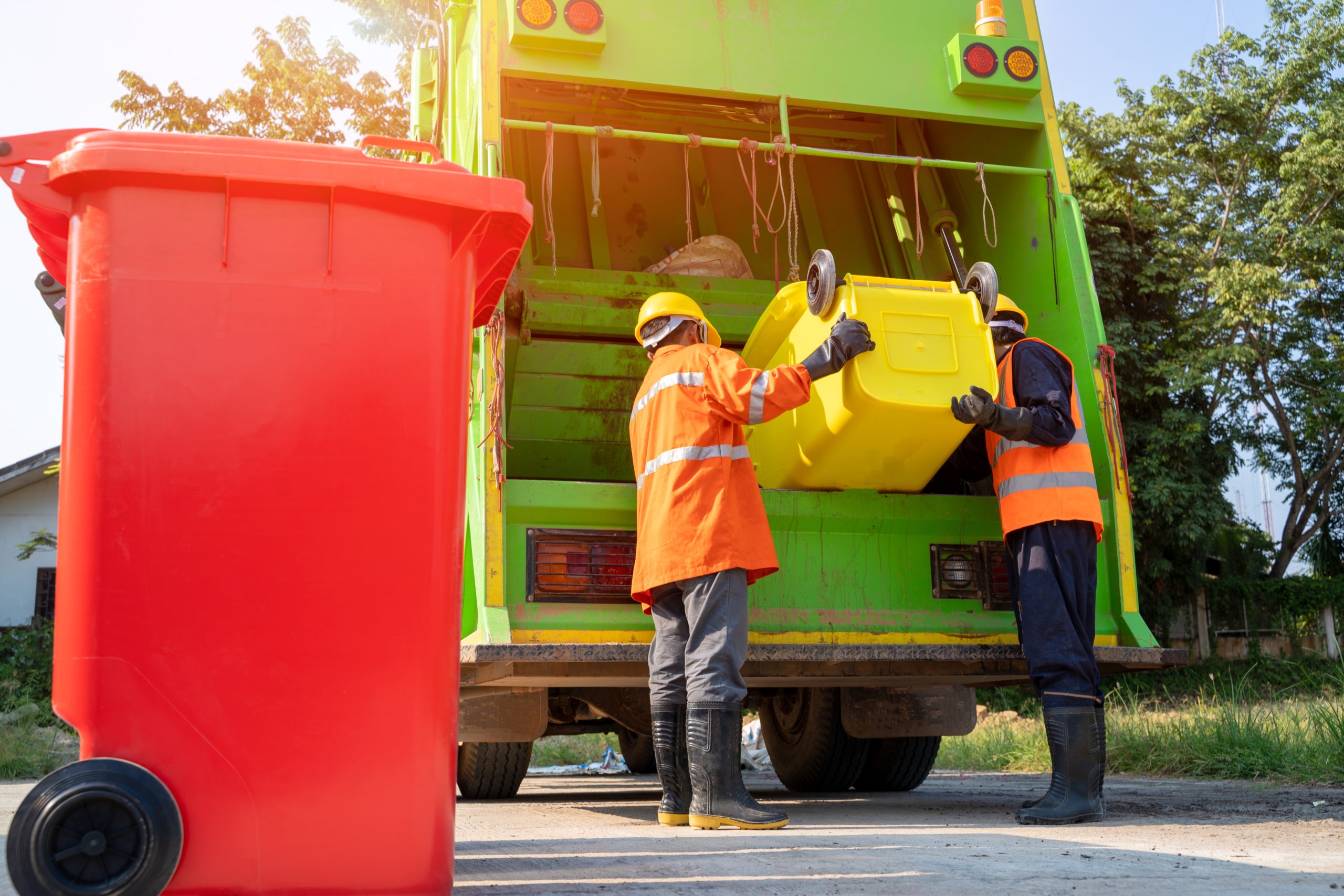 Two garbage men working together on emptying dustbins for trash
