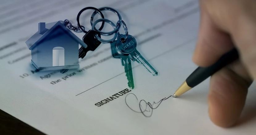 person signing a paper about home