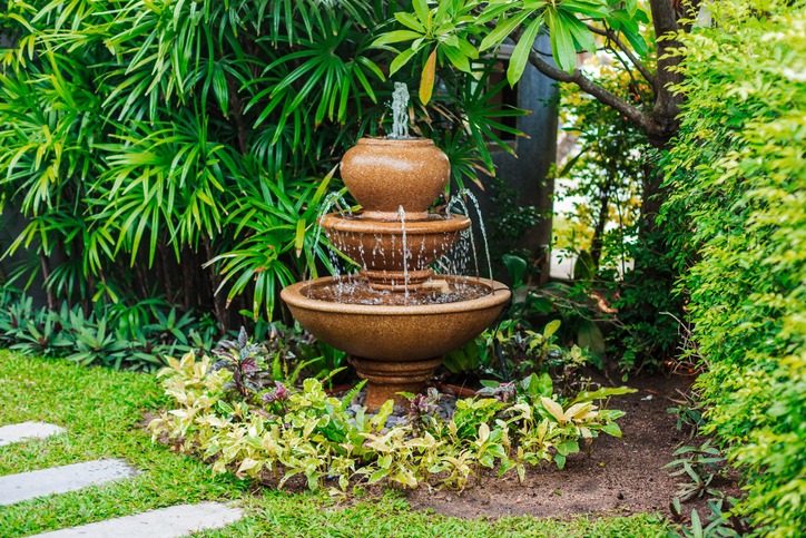 A brown outdoor water fountain near a walkway