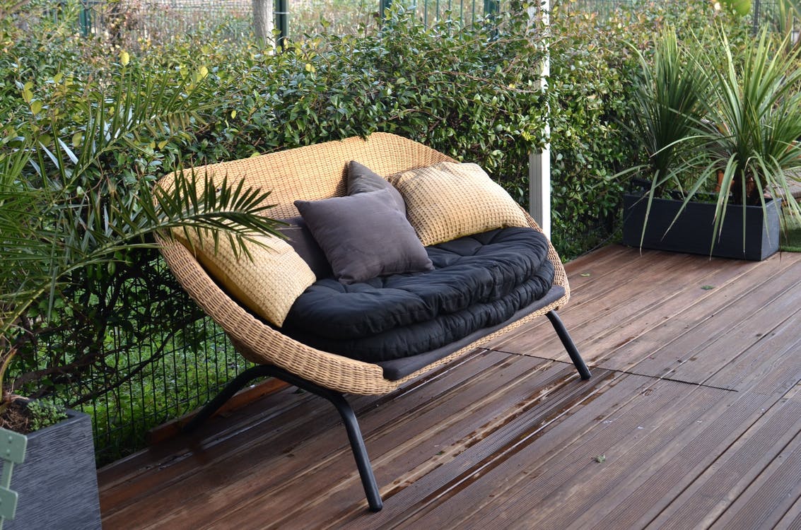 a cozy rattan sofa with cushions in a tropical garden