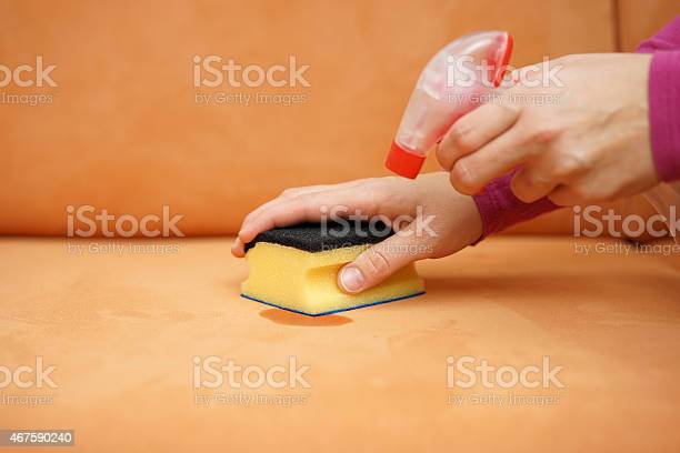 An orange couch being cleaned with a sponge and spray-in solution