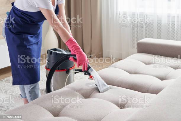 A woman vacuuming the couch