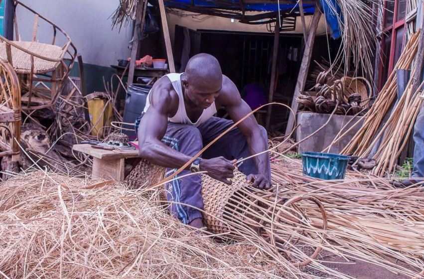 a black man weaving a basket using rattan