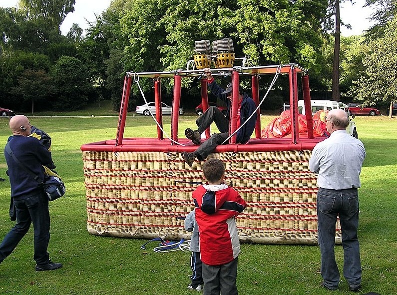 a hot air balloon basket made from wicker, and people around it