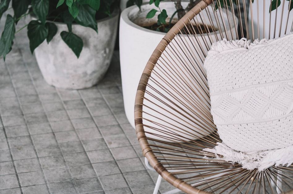 a white pillow on a wicker chair next to plants