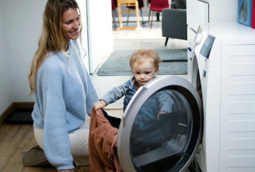 a-woman-and-baby-girl-looking-the-washing-machine